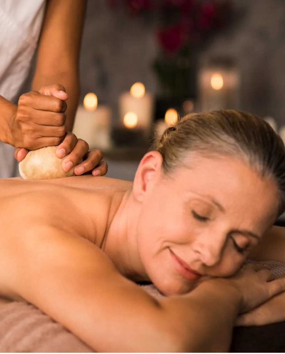 Practitioner performing Patra Pinda Sweda therapy on a patient’s shoulder